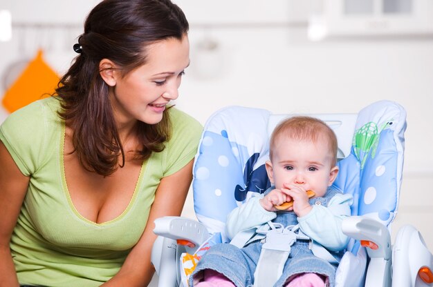 moeder kijkt op baby in de kinderstoel