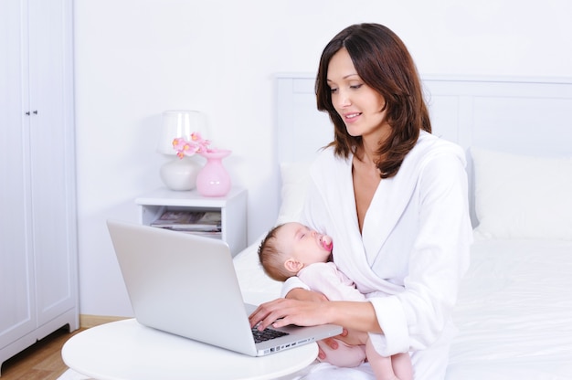 Moeder met baby met laptop in de kamer