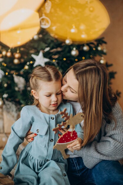 Moeder met dochter die kerstspeelgoed vasthoudt