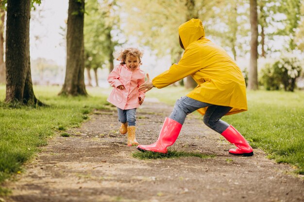 Moeder met dochter die pret in park in een regenachtig weer hebben