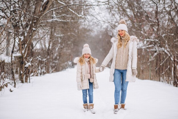 Moeder met dochter die samen in een de winterpark loopt