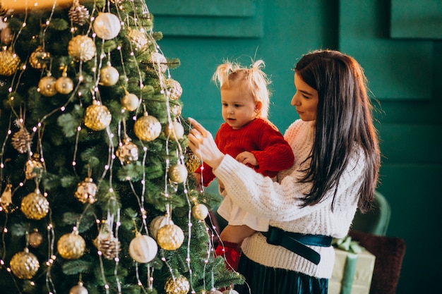 Moeder met dochter hangend speelgoed op kerstboom
