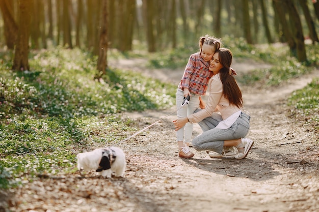 Moeder met dochter in een voorjaar bos met hond
