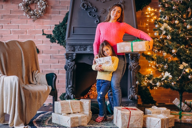 Moeder met dochter verpakking aanwezig bij open haard op Kerstmis