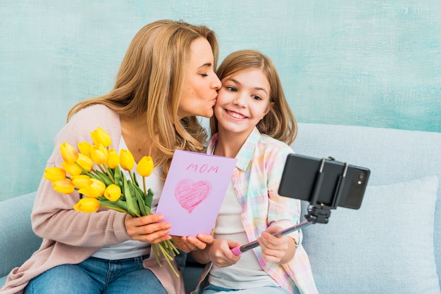 Gratis foto moeder met giften die dochter kussen die selfie nemen