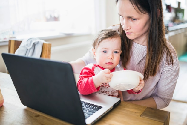 Gratis foto moeder met haar baby met behulp van laptop