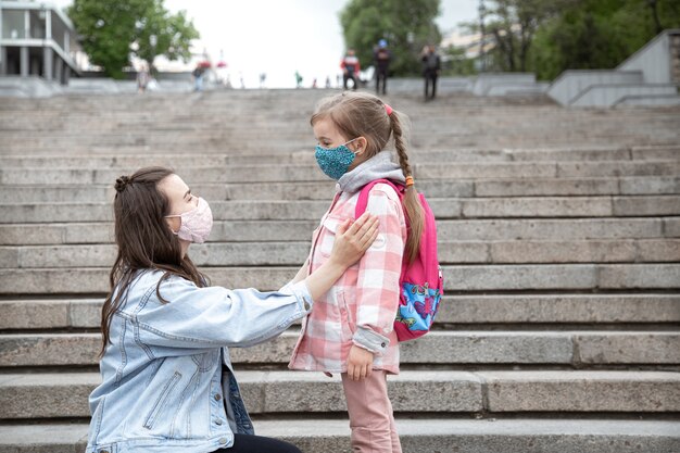 Moeder met haar dochtertje, een schoolmeisje, op de trap op weg naar school. Coronavirus pandemie onderwijsconcept.