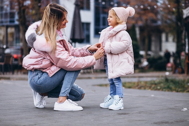 Moeder met haar dochtertje gekleed in warme doek buiten de straat