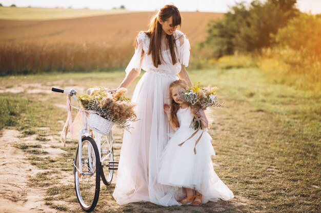 Moeder met haar kind in prachtige jurken met fiets
