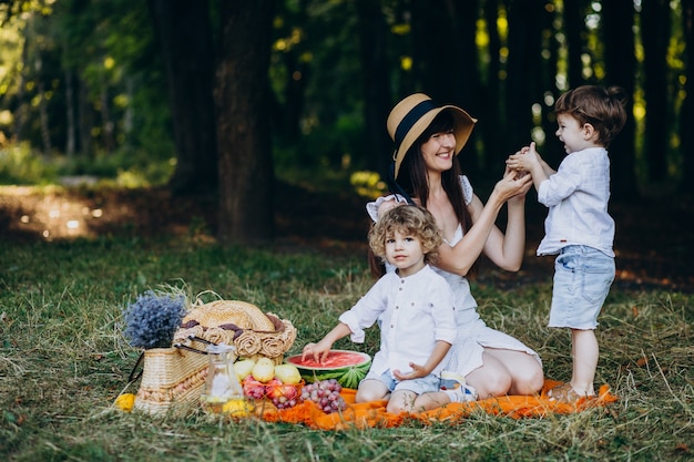 Moeder met haar zonen die picknick in bos hebben