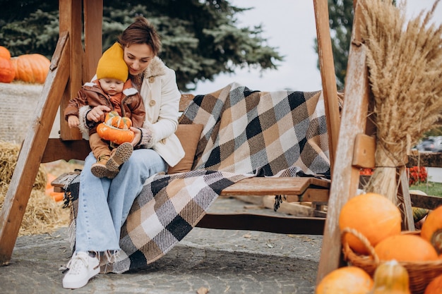 Moeder met haar zoontje bij de pompoenen op halloween