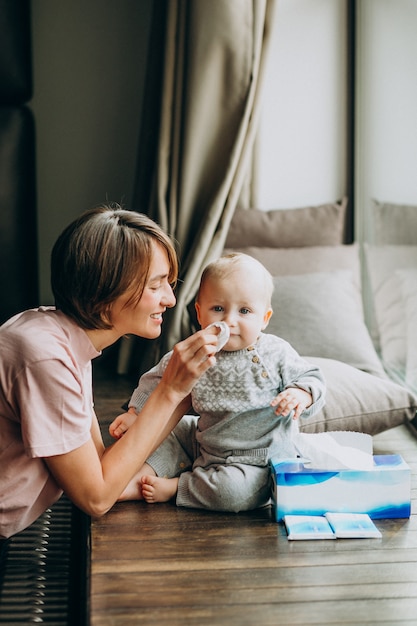 Moeder met haar zoontje met servetten voor loopneus