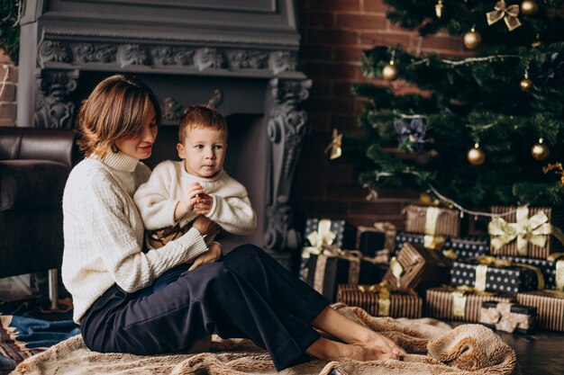 Moeder met haar zoontje zitten door de kerstboom