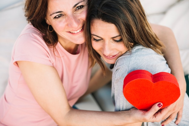 Gratis foto moeder met hartvormige doos omarmen vrouw