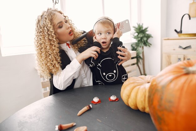 Moeder met kind in kostuums en make-up. Familie bereidt zich voor op de viering van Halloween.