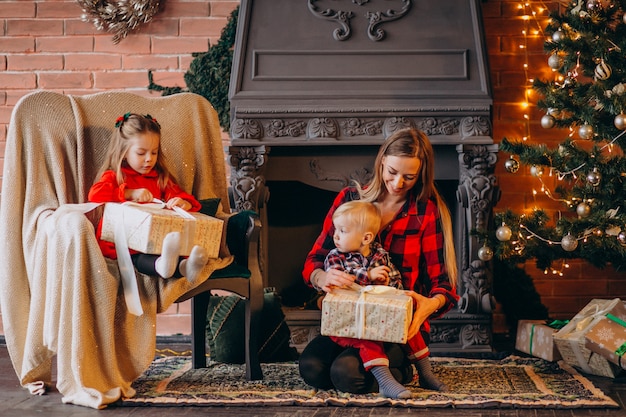 Moeder met kinderen door kerstboom