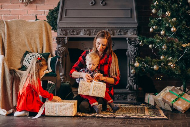 Moeder met kinderen door kerstboom