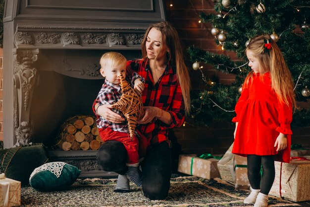 Moeder met kinderen door kerstboom