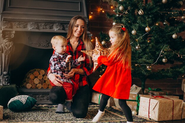 Moeder met kinderen door kerstboom