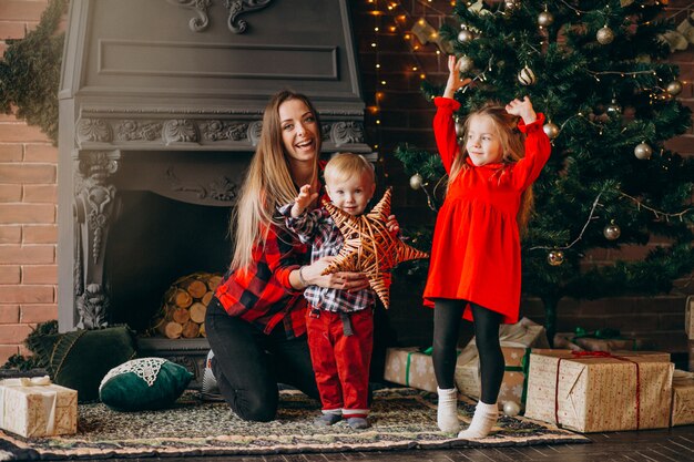 Moeder met kinderen door kerstboom