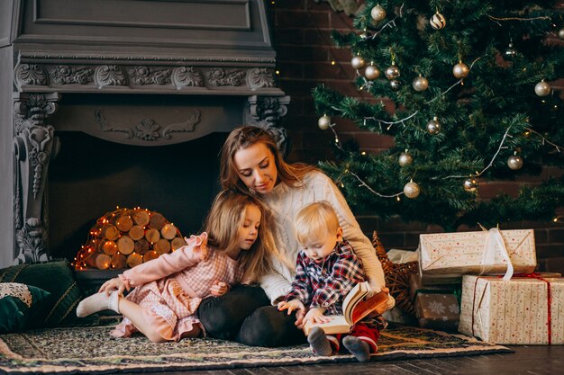 Moeder met kinderen door kerstboom