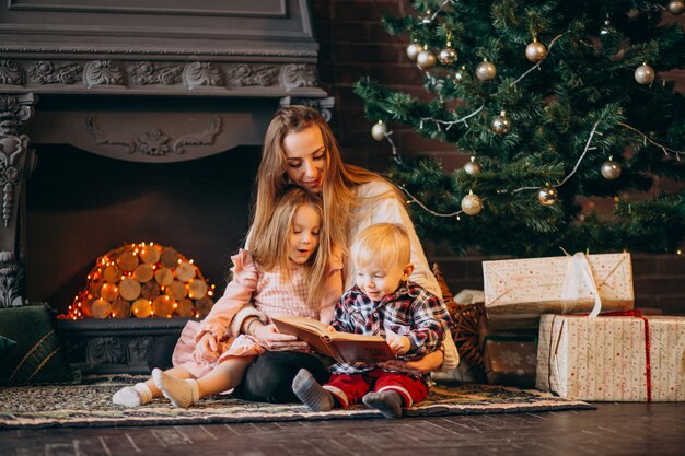 Moeder met kinderen door kerstboom