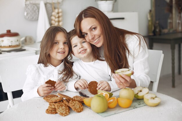 Moeder met kinderen zitten in een keuken en eten