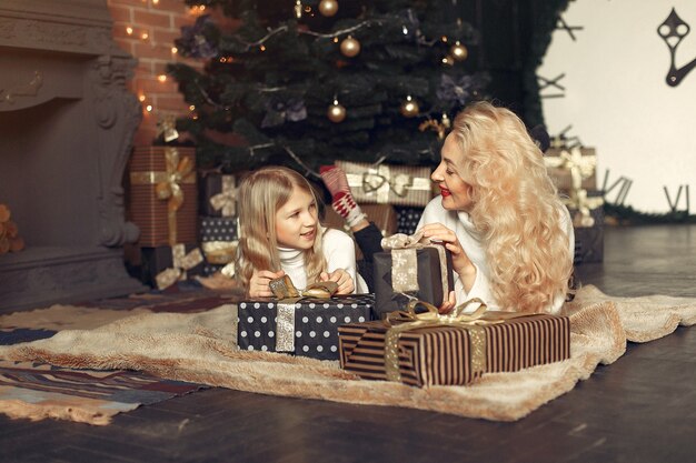 Moeder met schattige dochter thuis in de buurt van kerstboom