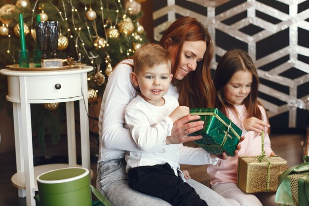 Moeder met schattige kinderen in de buurt van kerstboom