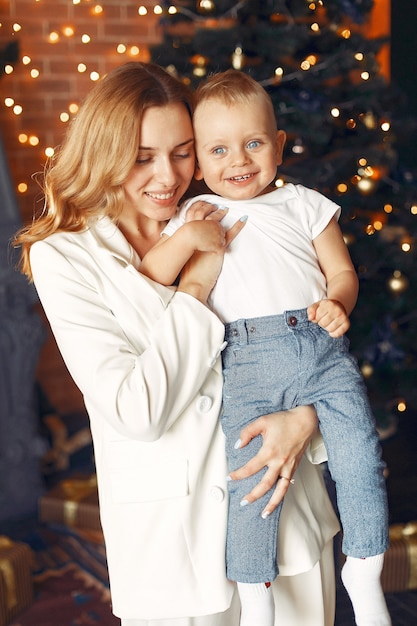 Moeder met schattige zoon thuis in de buurt van kerstboom