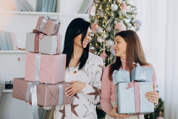 Moeder met volwassen dochter met kerstcadeautjes door kerstboom