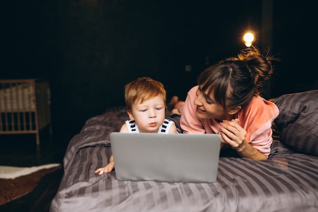 Moeder met zoon die aan computer in bed werkt