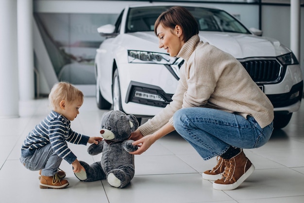 Moeder met zoon in een autoshowroom die met teddybeer speelt