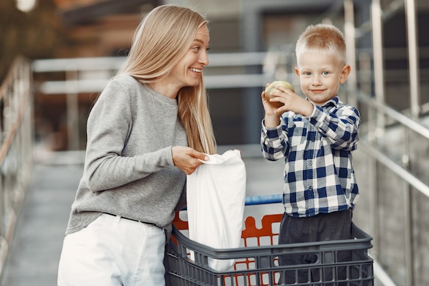 Moeder rijdt in een karretje. Familie op een parkeerplaats bij een supermarkt.