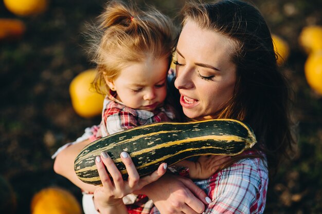 Moeder speelt met haar dochter op een veld met pompoenen, halloween vooravond