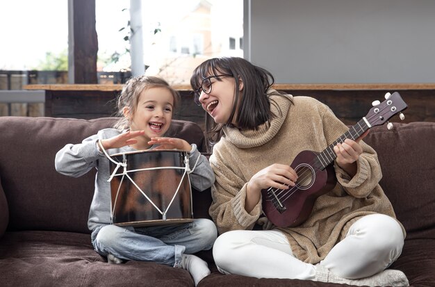 Moeder speelt thuis met haar dochter. Lessen over een muziekinstrument. Ontwikkeling en gezinswaarden van kinderen. Het concept van vriendschap en familie van kinderen.