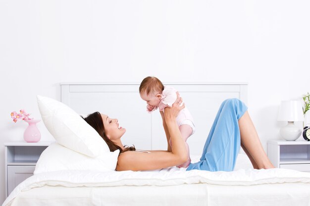 Moeder spelen met baby op het bed