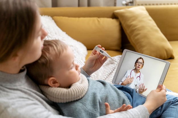 Moeder zorgt voor haar kind en teleconsulteert met dokter