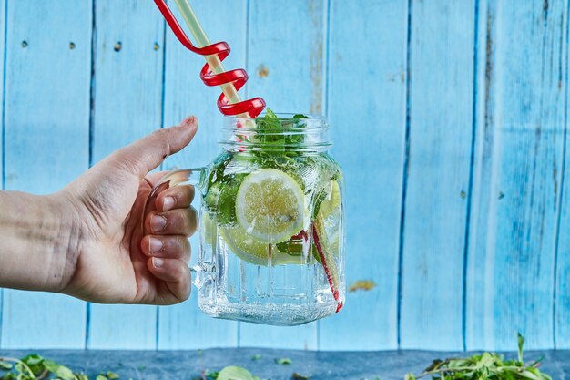 Mojito cocktail met plakjes limoen en munt op blauwe tafel met verse muntblaadjes