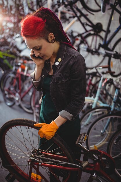 Monteur praten over de mobiele telefoon tijdens het repareren van de fiets