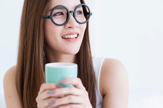 Mooi aantrekkelijk aziatisch meisje wit t-shirt geniet van weekendvakantie met warme drank in witte interieur kamer achtergrond