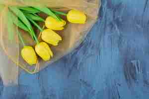 Gratis foto mooi boeket verse gele tulpen op blauw.