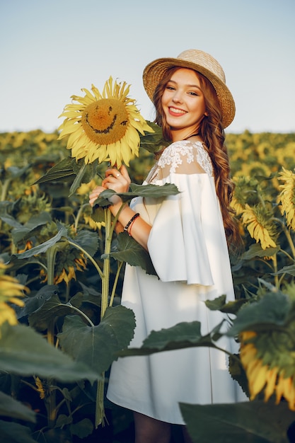 Mooi en stijlvol meisje in een veld met zonnebloemen
