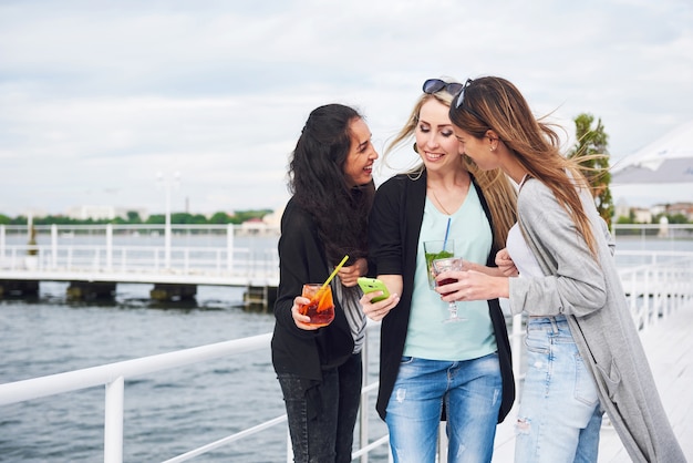 Mooi glimlachend meisje op een pier in de buurt van water. Positieve emoties.