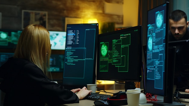 Mooi hackermeisje dat met een andere gevaarlijke cybercriminelen werkt. Hackers centrum.