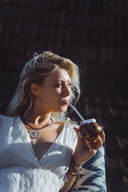 Mooi Indisch hippiemeisje met lang blond haar op de dak het drinken partnerthee.