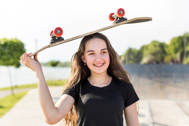 Gratis foto mooi jong meisje met een skateboard op haar hoofd