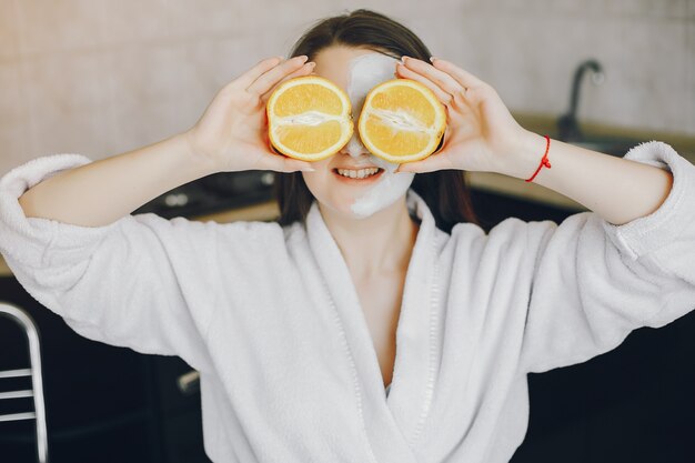 mooi jong meisje met lang haar en witte robe met een masker op het gezicht om thuis te zitten