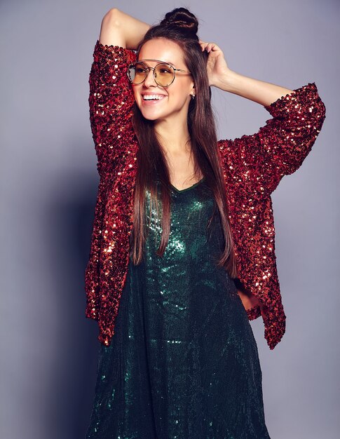 Mooi Kaukasisch het glimlachen hipster donkerbruin vrouwenmodel in heldere glanzend wijzend op de zomer modieus jasje en het groene kleding stellen op grijs