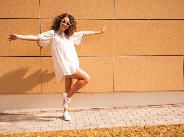 Mooi lachende model met afro krullen kapsel gekleed in zomer hipster witte jurk.